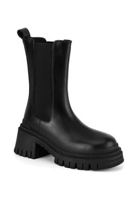 Botină din piele neagră până la gleznă, cu panouri laterale elastice, vârf rotund și talpă platformă masivă cu margine zimțată pentru aderență.