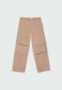 Pantalones de pierna ancha beige, confeccionados en una tela ligera, con dos grandes bolsillos delanteros y cordones elásticos en la cintura y los dobladillos.