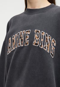 Σκούρο γκρι φούτερ με το κείμενο "ANINE BING" σε μεγάλα, ραμμένα γράμματα που διαθέτουν καφέ και μαύρο μοτίβο λεοπάρδαλης.
