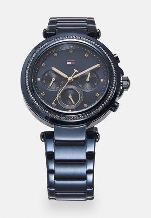 Montre en acier inoxydable noir avec un cadran noir texturé, aiguilles dorées, trois sous-cadrans et accents en cristal sur la lunette. Bracelet argenté.