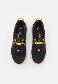 Scarpe sportive nere con tomaia in mesh, accenti rosa vivaci, lacci gialli e suole bianche. Presentano un collare imbottito e una superficie testurizzata.