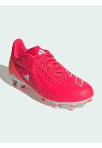 Scarpini da calcio rosa brillante con upper sintetico liscio, sei tacchetti argento e accenti bianchi del logo. Presenta una chiusura tradizionale con lacci.