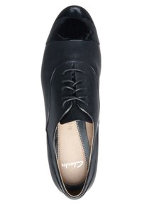 Chaussure noire en cuir à lacets avec un bout de la chaussure brillant noir, une texture lisse et une semelle intérieure beige contrastante avec logo. Design élégant, forme classique.