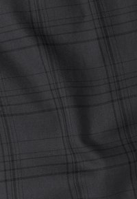 Tissu à motif à carreaux gris foncé, avec des fines lignes tissées dans un tissu lisse, créant une texture subtile et de la profondeur.