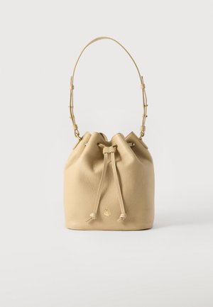 Beige leather bucket bag with adjustable strap and drawstring closure, displayed against a plain white background.