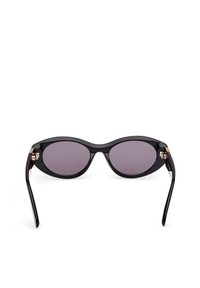 Černé sluneční brýle ve tvaru kočičích očí s tmavě fialovými čočkami, lesklým povrchem a zlatými detaily na stranách. Hladký povrch a zakřivený tvar.