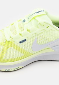 Baskets de course en maille jaune avec un swoosh Nike blanc, tige texturée, lacets et semelle en caoutchouc dotée de la technologie Zoom.