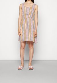 Vestido sin mangas con cintura ajustada, presenta un patrón zigzag colorido en rosa, amarillo y azul; llega por encima de la rodilla.
