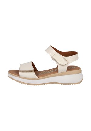 Sandalias blancas con tiras texturizadas, un cierre ancho de velcro y una plantilla acolchada. La suela de plataforma presenta un fondo beige en contraste.