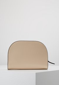 Beige läderpåse med rundad topp och slät yta. Har en svart kant och en sidodragkedja för öppning. Minimalistisk design.