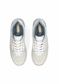 Paired de baskets blanches et gris clair à lacets avec semelles beiges et semelles intérieures de marque, vues directement de dessus sur un fond blanc.