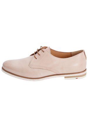 Beżowy skórzany but oksfordzki sznurowany z niskim obcasem i białą gumową podeszwą, pokazany z zewnętrznej strony na białym tle.