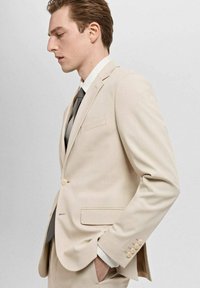 Beige Anzugjacke mit Reverskragen und einem Knopf. Verfügt über zwei Taschen, drei-Knopf-Manschette und eine glatte Textur. Graue Krawatte.