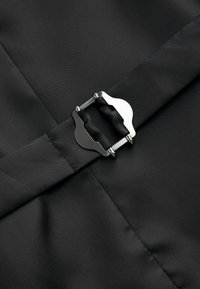 Un tissu noir au toucher lisse présente une boucle en métal argenté au centre, mettant en valeur un design épuré et minimaliste.