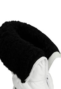 Witte pufferjack met een dikke, gestructureerde zwarte kraag en witte ritsdetails, met een zachte, pluizige afwerking zichtbaar op de rand van de kraag.
