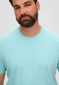 Lichtblauw t-shirt met korte mouwen en ronde hals. Gemaakt van een zachte, gestructureerde stof. Straksluitende stijl, minimalistisch ontwerp, geen zichtbare patronen.