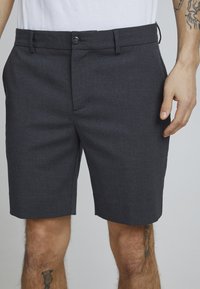 Grå shorts laget av teksturert stoff, med en rettskåret design, knappelukking og sidelommer.