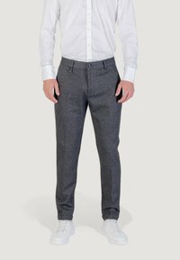 Pantaloni grigi su misura realizzati in un tessuto testurizzato, caratterizzati da un design a gamba dritta, tasche anteriori e chiusura con bottone. Indossati con sneakers bianche.