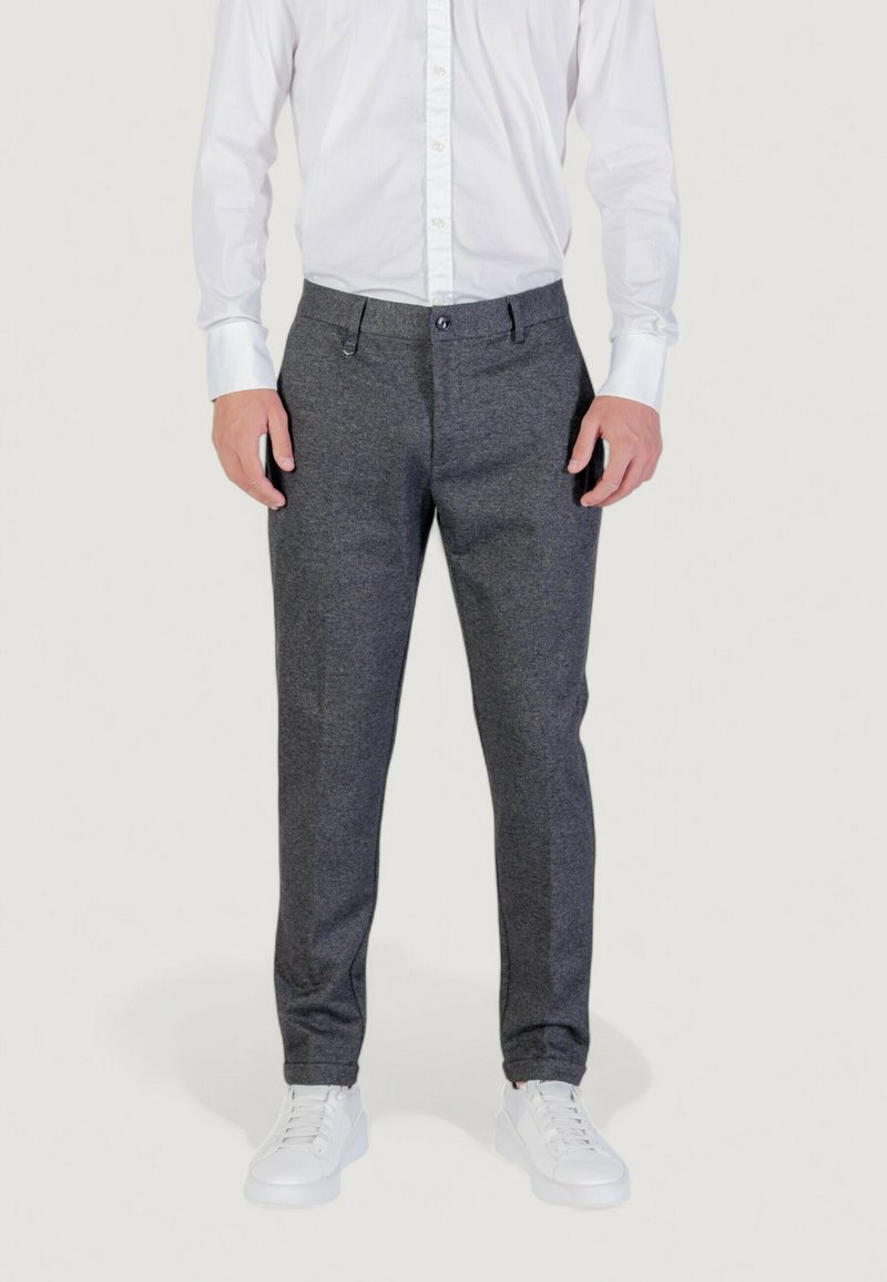 Pantaloni grigi su misura realizzati in un tessuto testurizzato, caratterizzati da un design a gamba dritta, tasche anteriori e chiusura con bottone. Indossati con sneakers bianche.