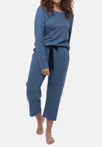 Sininen pitkähihainen paita, joka on yhdistetty lyhyisiin housuihin. Paita on valmistettu pehmeästä kankaasta, jossa on nyöritettävä vyötärö ja rento istuvuus.