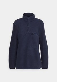 Sudadera de forro polar azul marino con cuello alto, cierre parcial con botones y bolsillo en el pecho con cremallera. Tejido texturizado y suave con mangas largas.