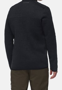 Giacca in pile grigio scuro con una finitura testurizzata e design aderente. Presenta un colletto alto e un'accortezza del logo sul retro.