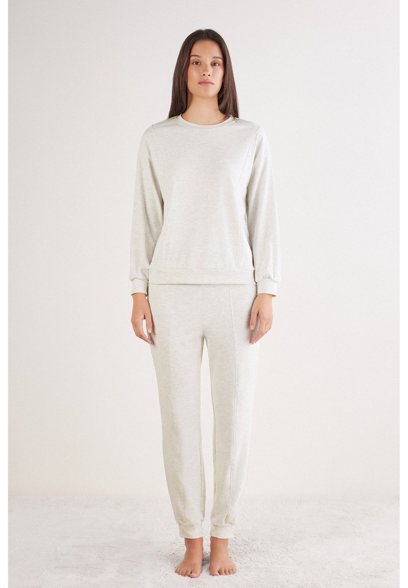Conjunto de ropa de casa en color gris claro, compuesto por un sudadera de manga larga y pantalones ajustados, con una textura suave y puños elásticos.