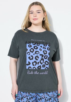 T-shirt en coton gris foncé à manches courtes avec un motif léopard bleu et le texte : "Achetez un billet pour N'IMPORTE OÙ" et "Règle le monde."