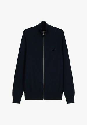 Pull en maille bleu marine à fermeture éclair intégrale avec poignets et col côtelés, arborant un petit logo rouge et blanc sur le côté gauche de la poitrine.
