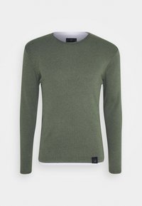 T-shirt à manches longues de couleur verte, fabriqué en matériau doux, avec un col rond et une étiquette décorative à l'ourlet. Design simple et ajusté.