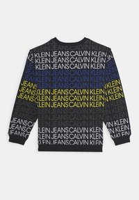 Sudadera negra con un patrón de texto repetido en blanco, azul y amarillo. Cuello redondo y puños de canalé; diseño casual unisex.