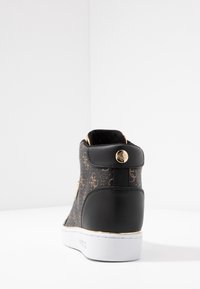 Wysokie trampki z czarnym skórzanym tyłem i brązowym wzorzystym materiałem. Posiadają złote elementy i białą gumową podeszwę.