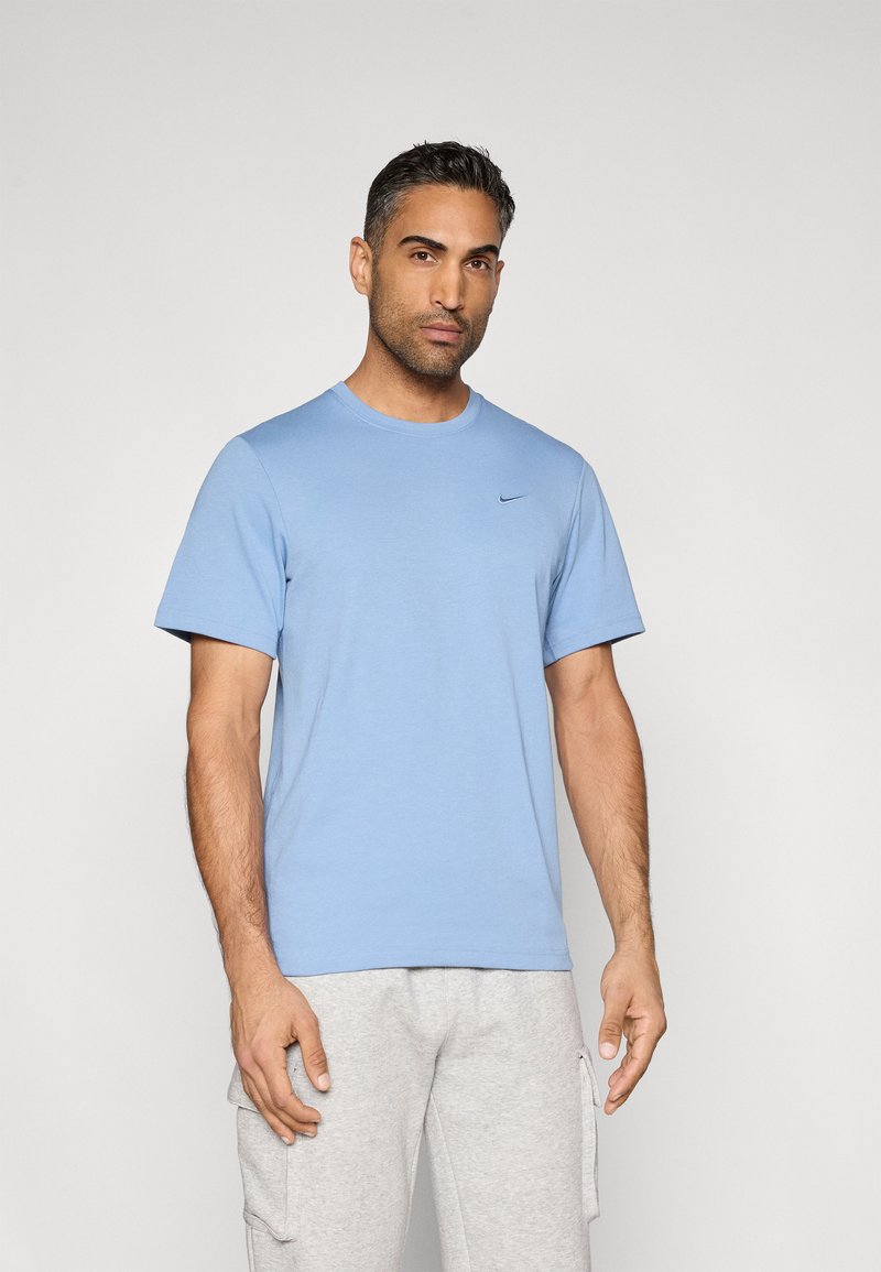 Ανοιχτό μπλε t-shirt με στρογγυλή λαιμόκοψη, κατασκευασμένο από απαλό ύφασμα, με κοντά μανίκια και μικρό μαύρο λογότυπο στο στήθος. Κανονική εφαρμογή.