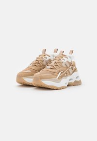 Sneaker chunky beige e bianche con suole spesse, pannelli in rete e pelle, linguette con marchio e cuciture dettagliate, mostrati su uno sfondo bianco.