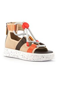 Sandale en filet beige et marron avec des accents orange et gris. Dotée d'une semelle mouchetée blanche et de lacets réglables avec un bouton rouge.