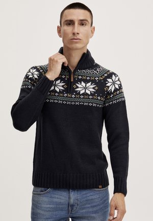 Marine gebreide half-zip trui met een patronen schouderstuk featuring witte sneeuwvlokken en kleurrijke accenten. Geribbelde manchetten en zoom, gestructureerd materiaal.