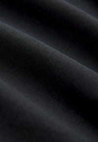 Close-up of black fabric showing fine texture and gentle folds with soft lighting.