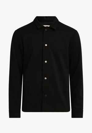 Chemise noire à boutons avec un tissu doux, un col et des manches longues. Présente des boutons en métal argenté sur le devant, au design minimaliste.