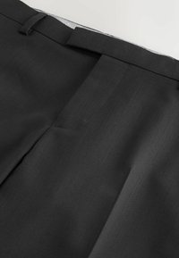 Schwarze maßgeschneiderte Hose mit glatter Textur, geradem Schnitt und verdeckten Frontverschlüssen. Mit Gürtelschlaufen und sauberem Finish.