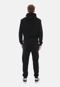 Black hoodie and sweatpants set with a relaxed fit, featuring ribbed cuffs and elastic waistband. Smooth texture and minimalistic design.