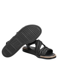 Mustat nahka-sandaalit, joissa on ristikkäiset hihnat ja tasapohja. Texturoitu kumipohja, jossa on vaakasuorat urat pitävyyden parantamiseksi.