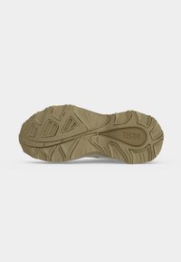 Semelle d'une basket beige Diesel avec des motifs de semelle texturés et le nom de la marque embossé près du talon.