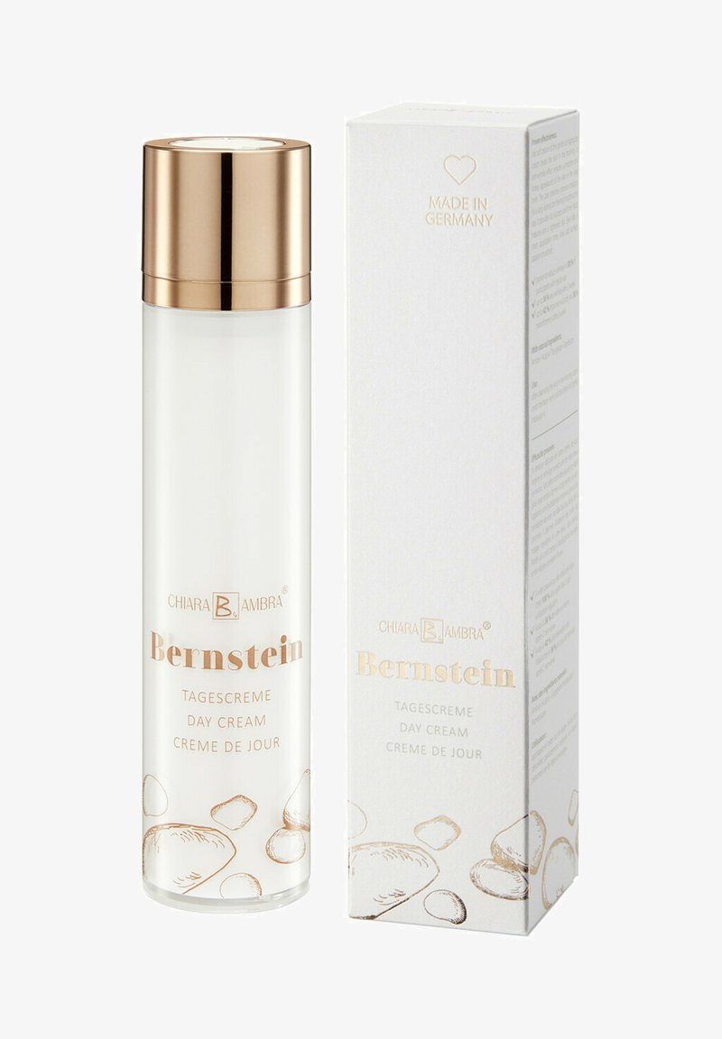 Clear glass bottle with a gold cap, labeled "Bernstein Tagescreme," next to a white box with gold accents and product information printed.