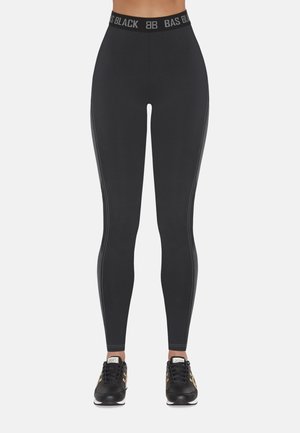 Czarne legginsy z szerokim elastycznym paskiem w talii z logo "BAS BLACK". Gładka tekstura z detalami bocznych paneli. Połączone z czarnymi butami sportowymi.