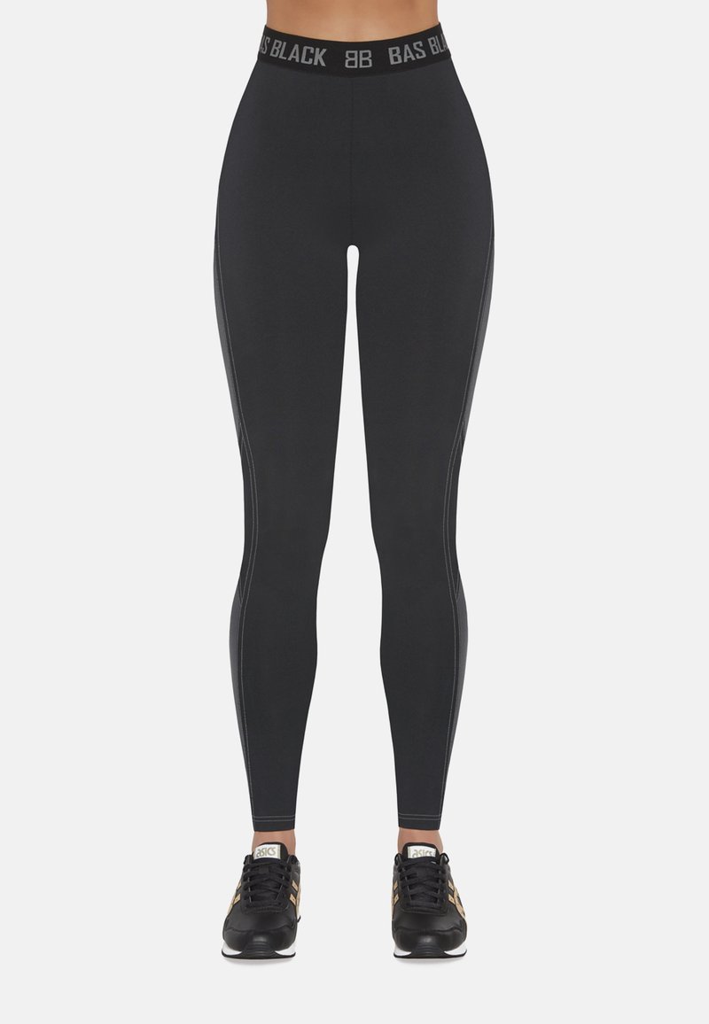 Czarne legginsy z szerokim elastycznym paskiem w talii z logo "BAS BLACK". Gładka tekstura z detalami bocznych paneli. Połączone z czarnymi butami sportowymi.