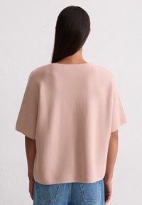 Jasnoróżowa, dziergana bluzka o luźnym kroju i krótkich rękawach, z okrągłym dekoltem i subtelnym wzorem teksturowym.