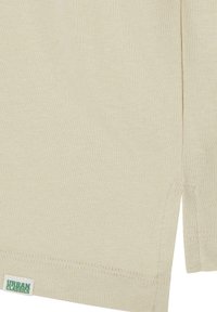 Camiseta de algodón beige con una textura suave, que presenta cortes laterales y una pequeña etiqueta verde en el dobladillo con la inscripción "URBAN CLASSICS".