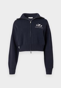 Tumši zila īsa džemperu jaka ar rāvējslēdzēju un augstu apkakli, ar ribotu aproču un jostasvietas malu, kā arī baltu izšūtu logo kreisajā krūtīs.