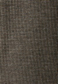 Tkanina tekstylna z wzorem houndstooth w ciemnoszarym i jasnobrązowym kolorze, z teksturowaną, tkaną powierzchnią.