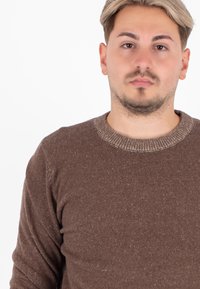 Maglione marrone lavorato a maglia con una superficie texturizzata, colletto a coste e maniche lunghe, caratterizzato da leggere sfumature nel tessuto.